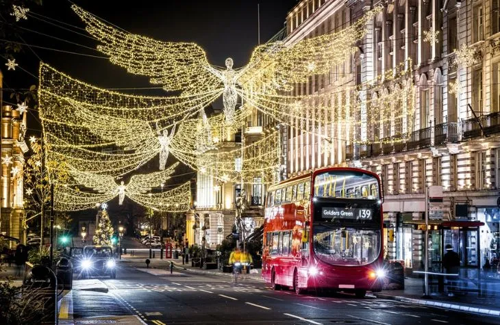 KT - A red bus under festive angel lights at night